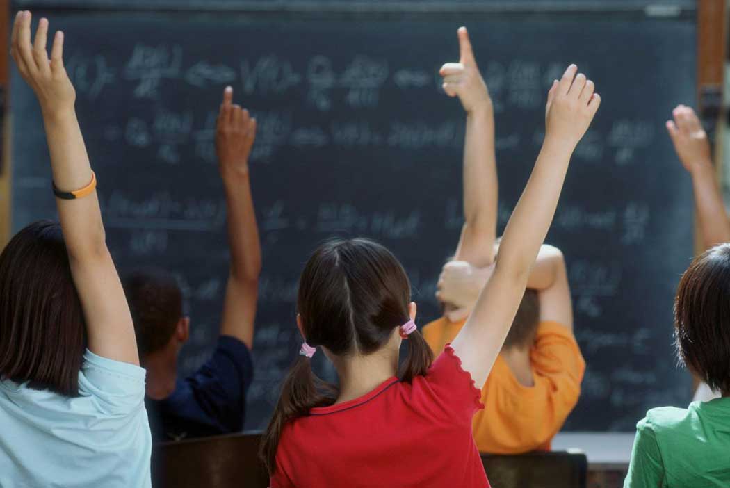 children raising their hands in a classroom