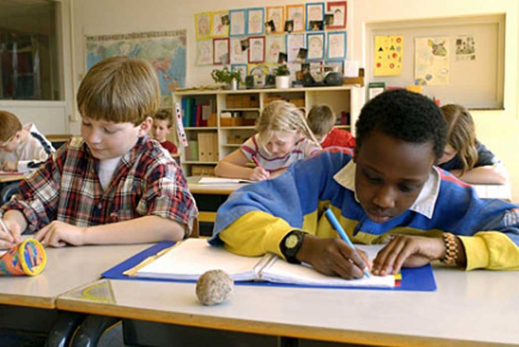 children at desks writing in notebooks